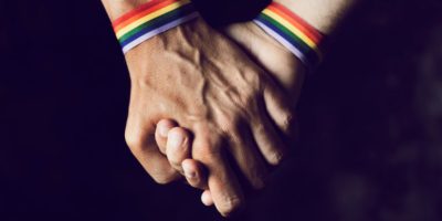 men holding hands with rainbow-patterned wristband